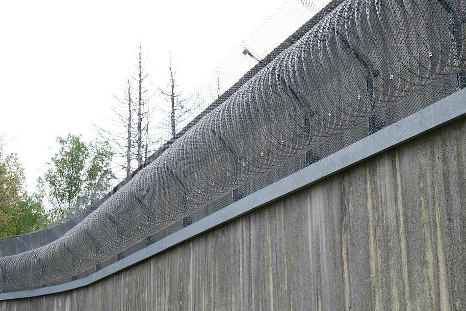 Eine Gefängnismauer aus Beton mit Widerhakensperrdraht