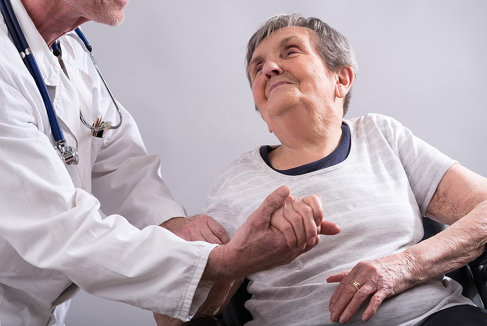 Arzt hält die Hand einer älteren Frau