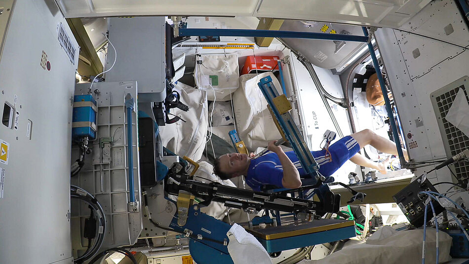 Astronaut auf der ISS beim Bankdrücken 