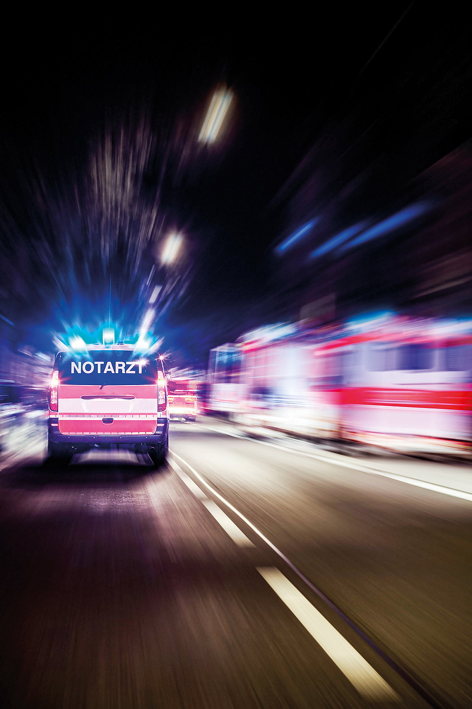 Krankenwagen fährt mit Blaulicht durch die Nacht