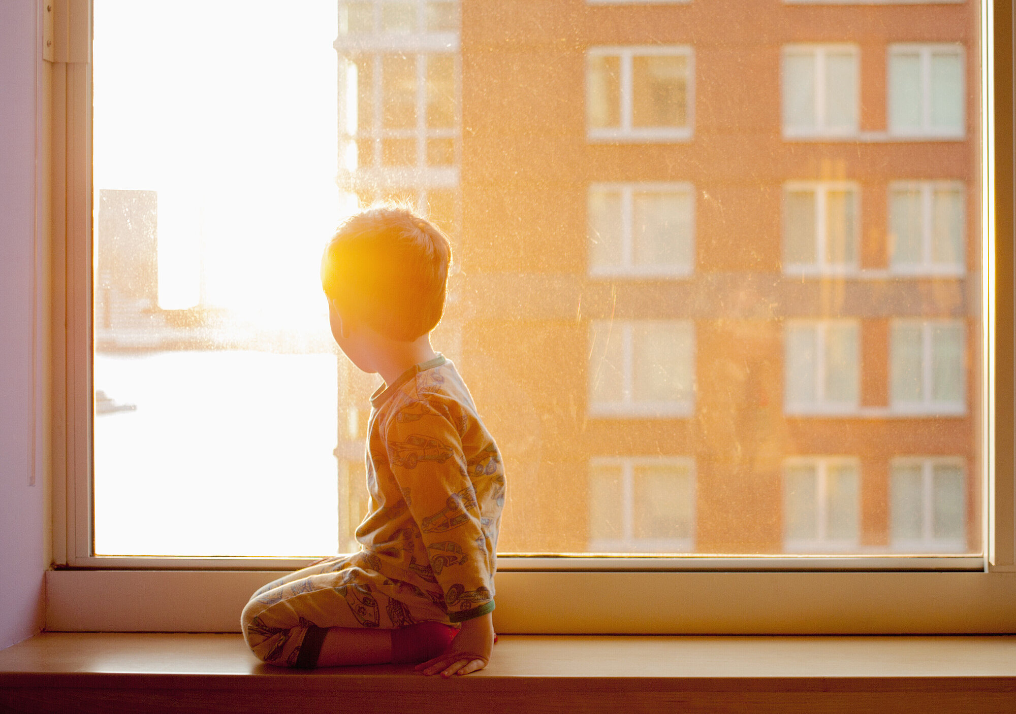 Kleiner Junge sitzt vor dem Fenster und schaut hinaus