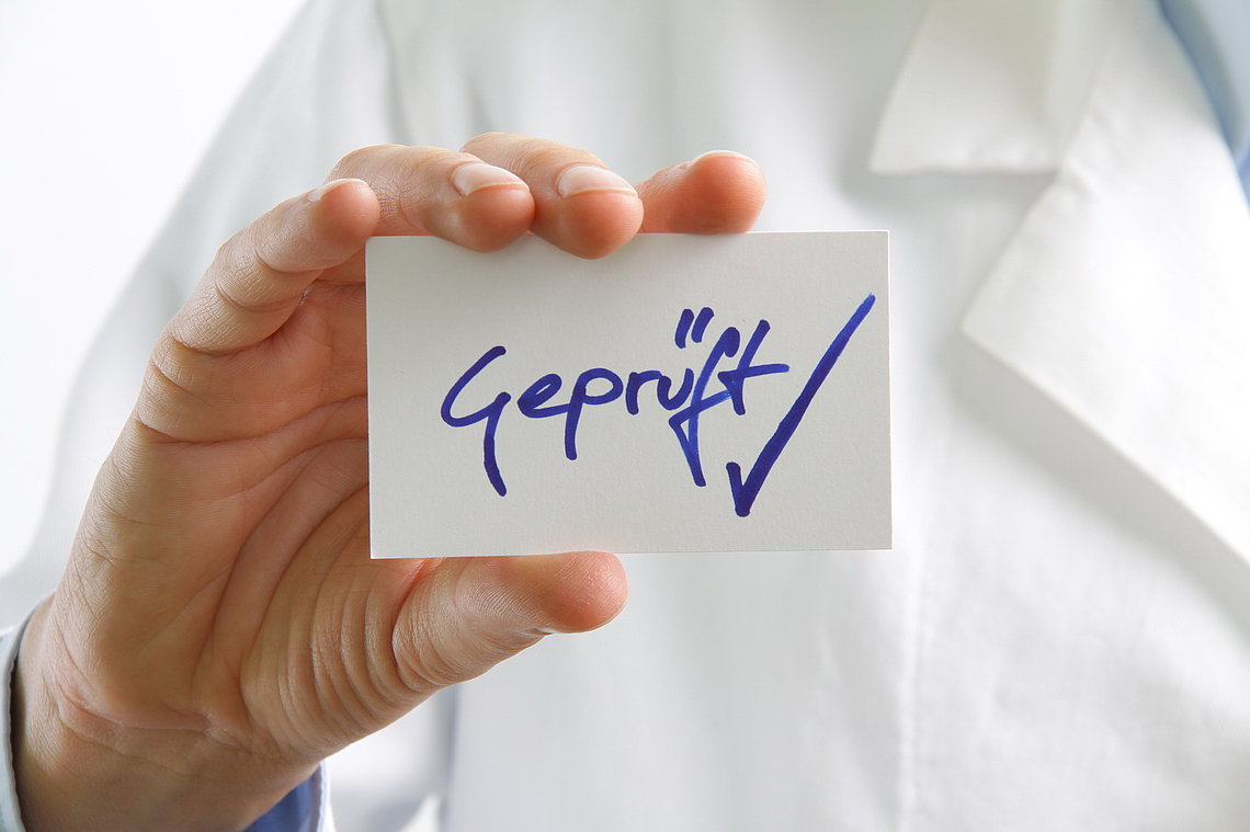 image-fachsprachpruefung.jpg Hand hält Karte "Geprüft"