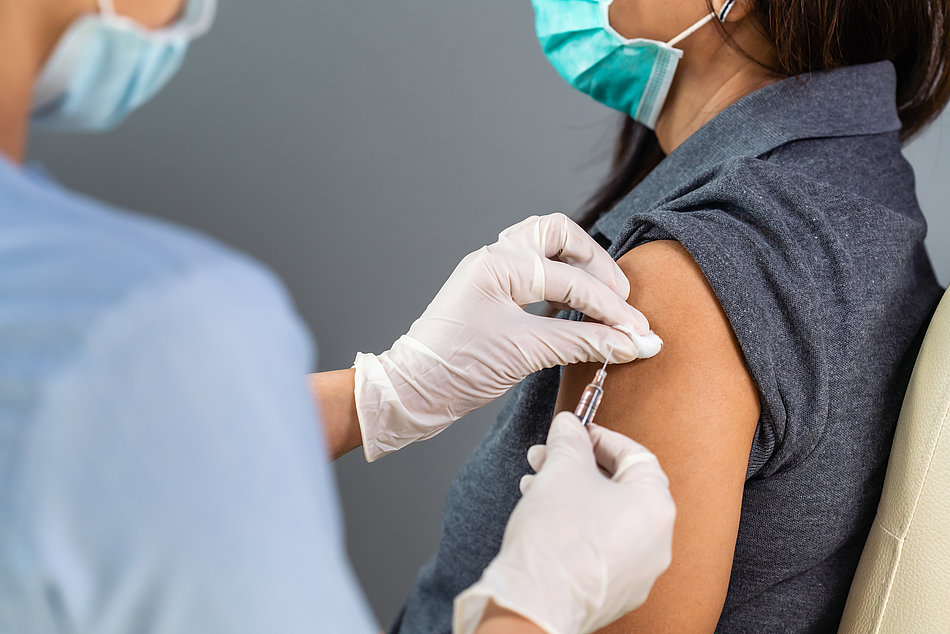 Ärztin impft eine junge Frau mit dem Impfstoff gegen COVID-19 in den Arm