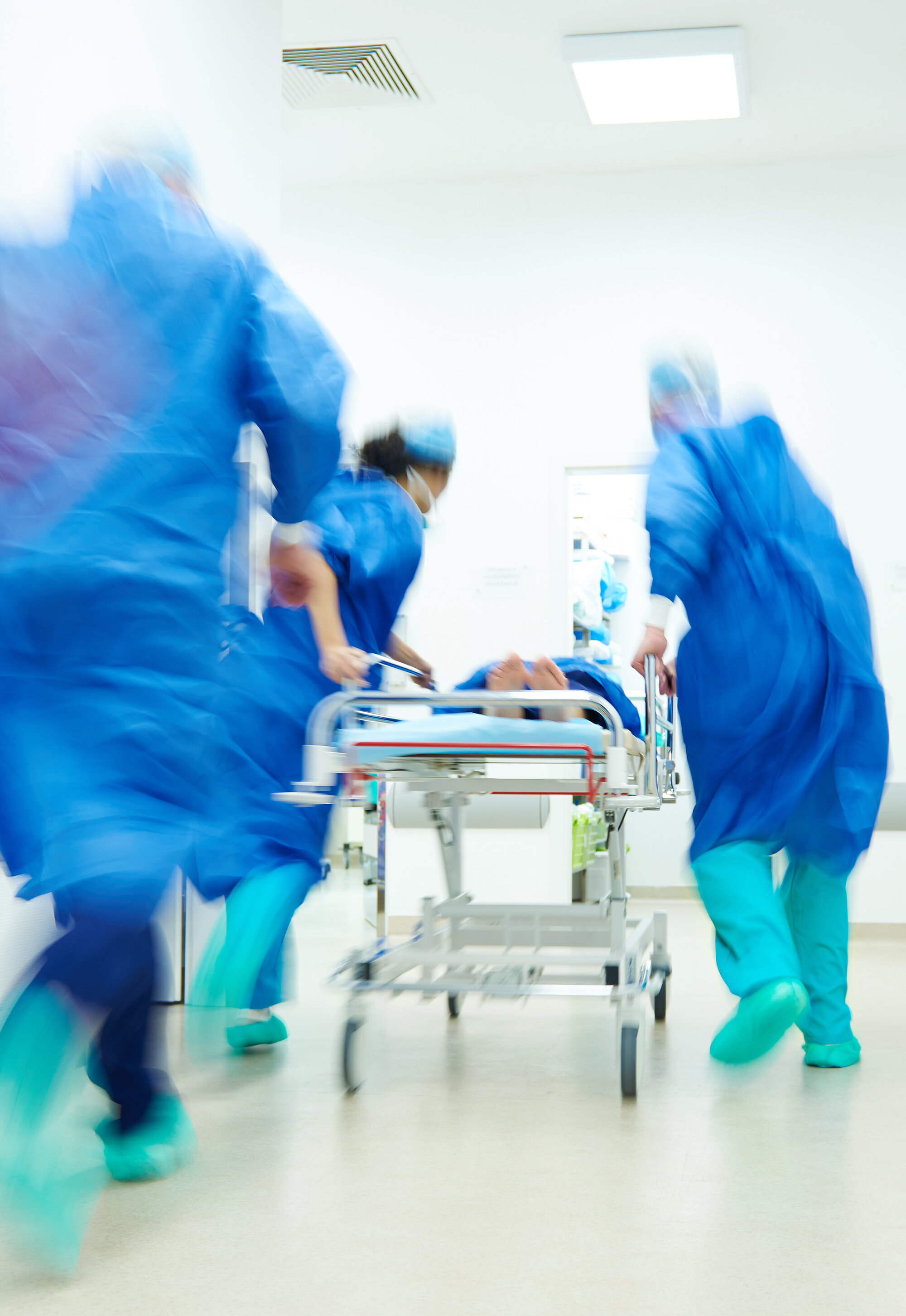 Ärzte rennen mit einem Krankenbett über den Flur eines Krankenhauses