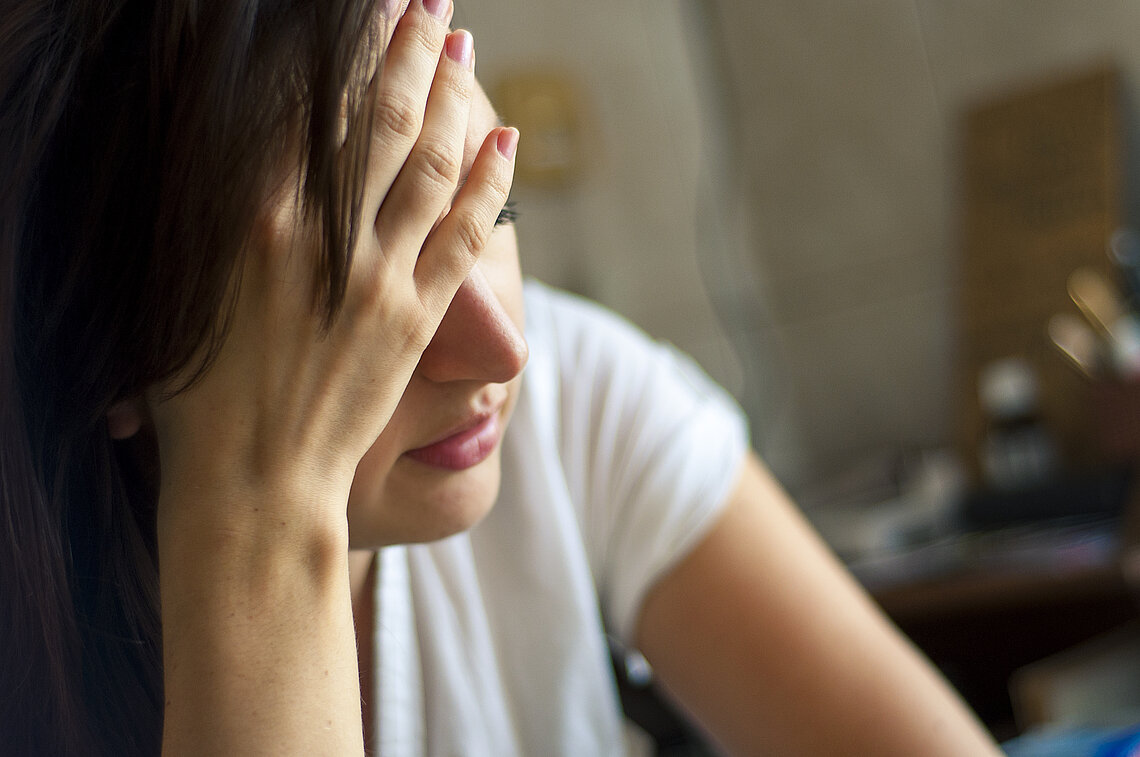 patient-belastet.jpeg Patientin legt Kopf erschöpft in den Händen ab