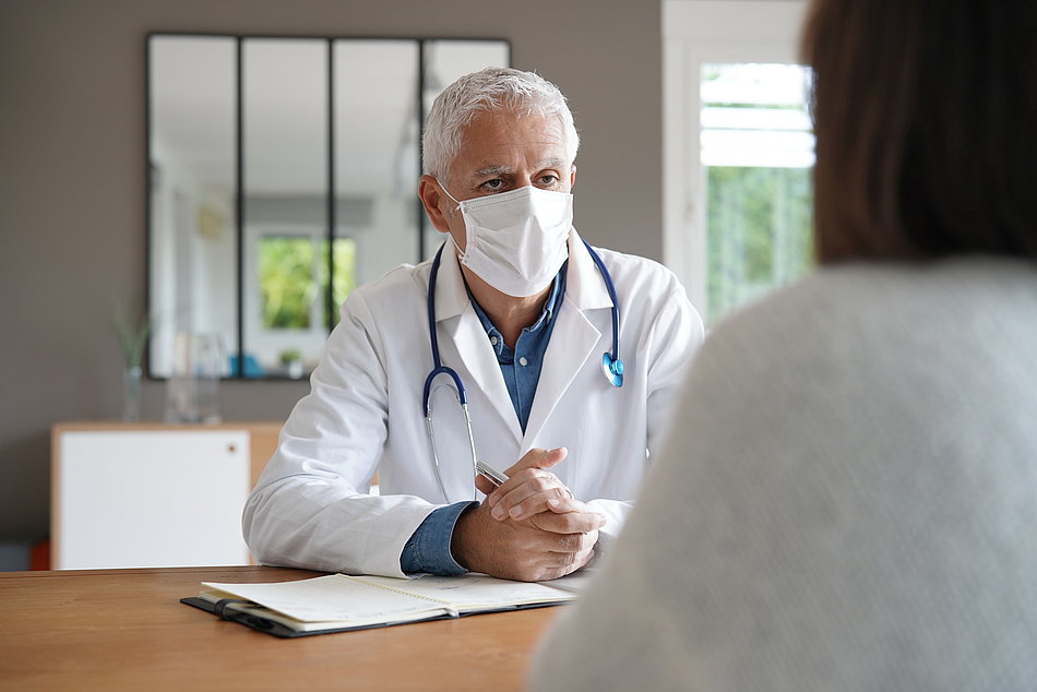 Arzt mit Maske im Patientengespräch