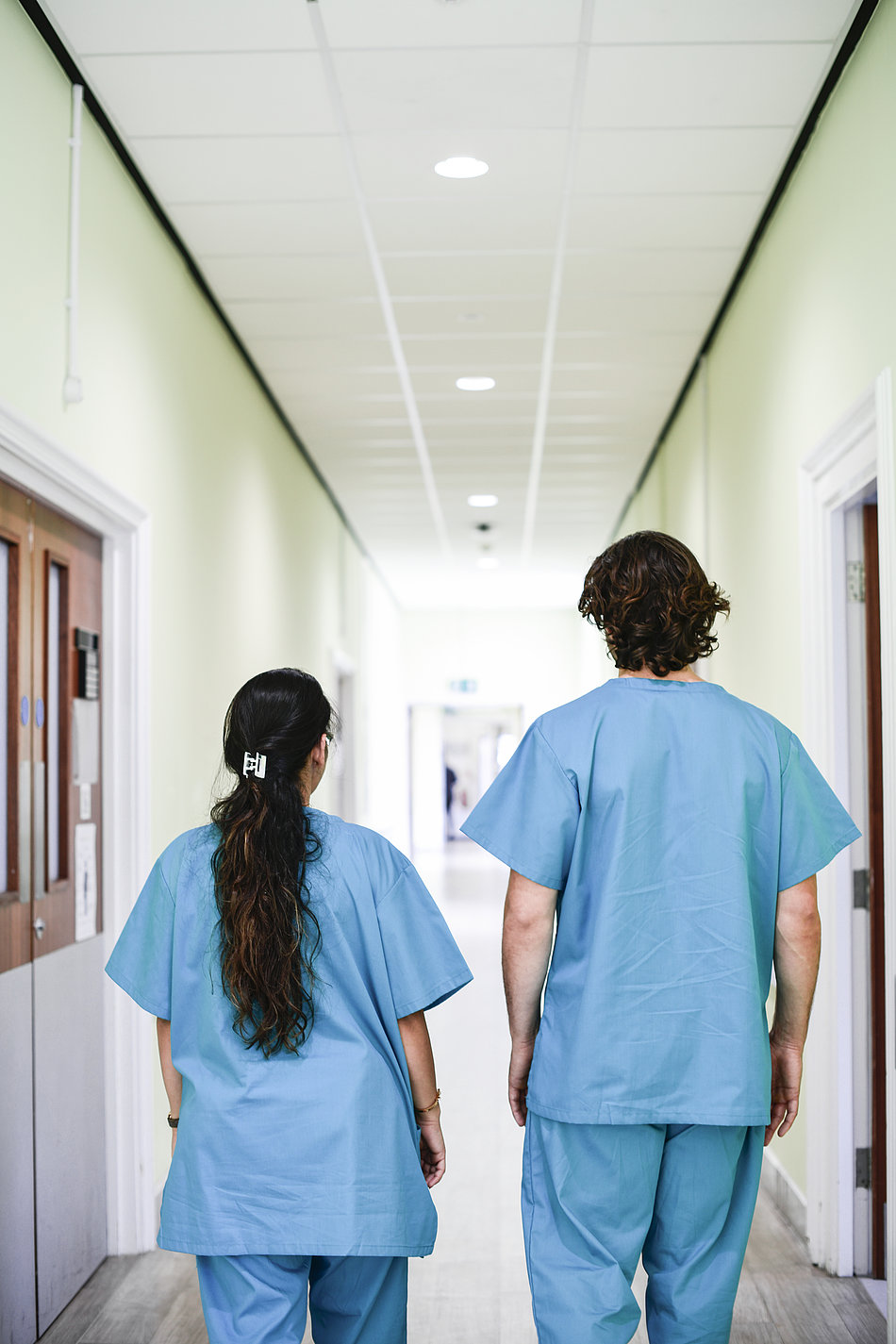 Zwei Pfleger laufen den Gang eines Krankenhauses herunter