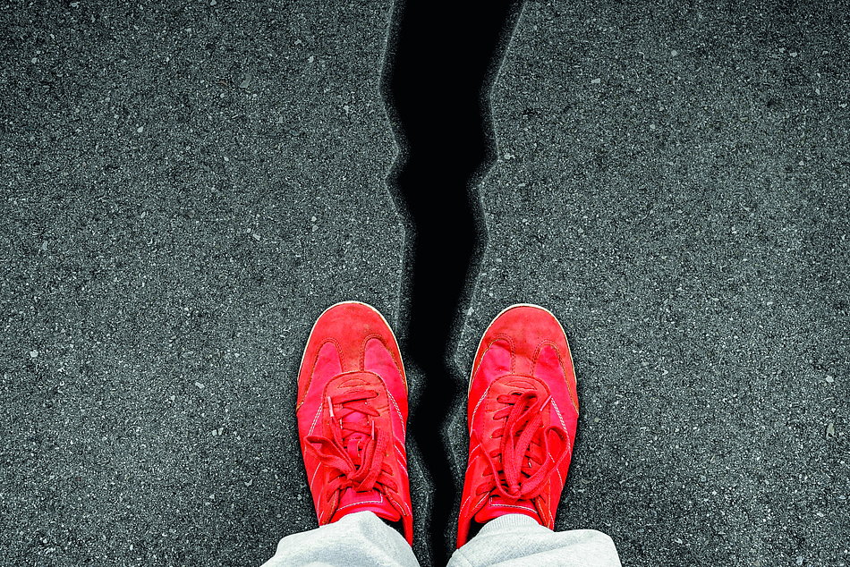 rote Schuhe über Spalte im Asphalt