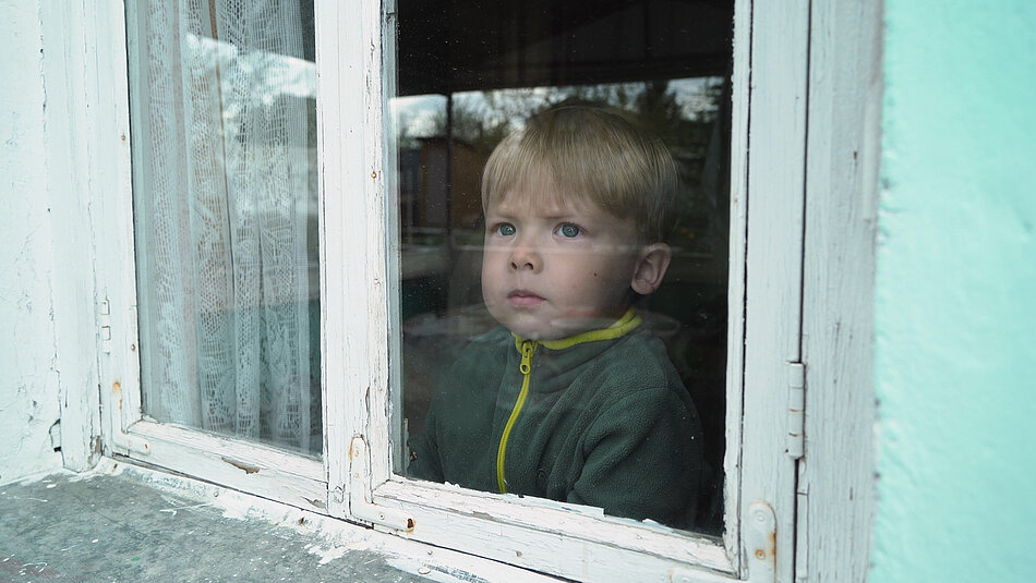 Ein trauriges Kind sitzt vor einem Fenster