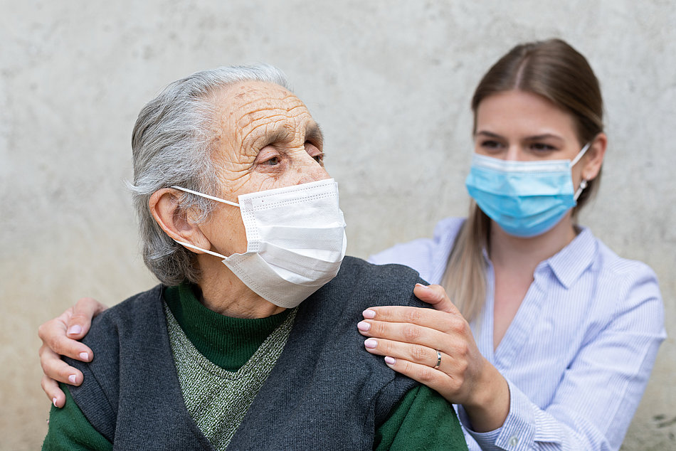 Ältere Dame und Pflegerin mit Masken