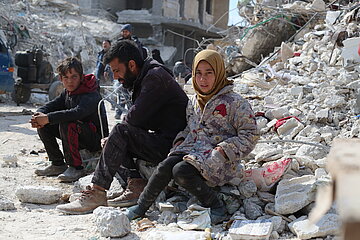 Erdbebenopfer sitzen vor Trümmern