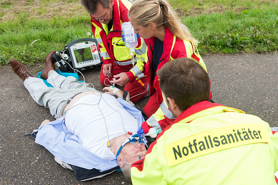 Notfallsanitäter versorgen einen am Boden liegenden Mann